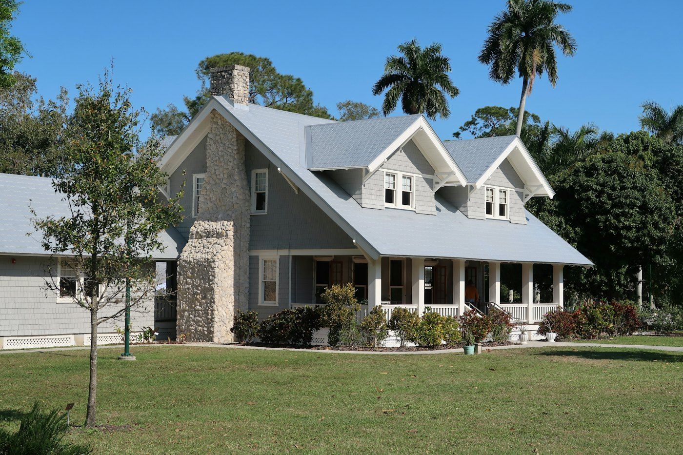 Ranch home with a stone chimney, royal palms and a big lawn