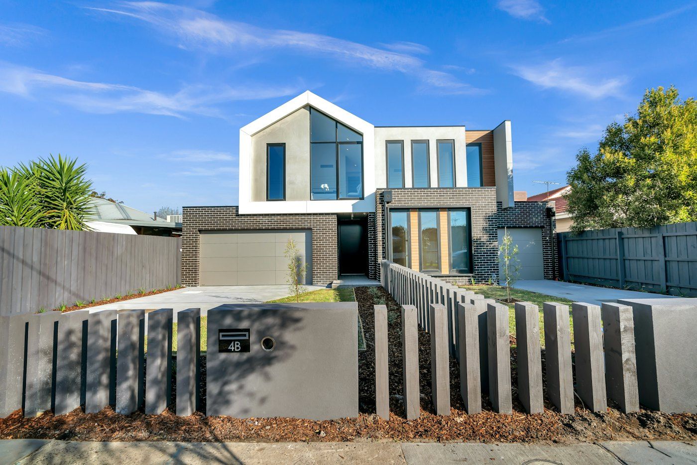 Modern two-story townhome with a garage behind a slatted front fence