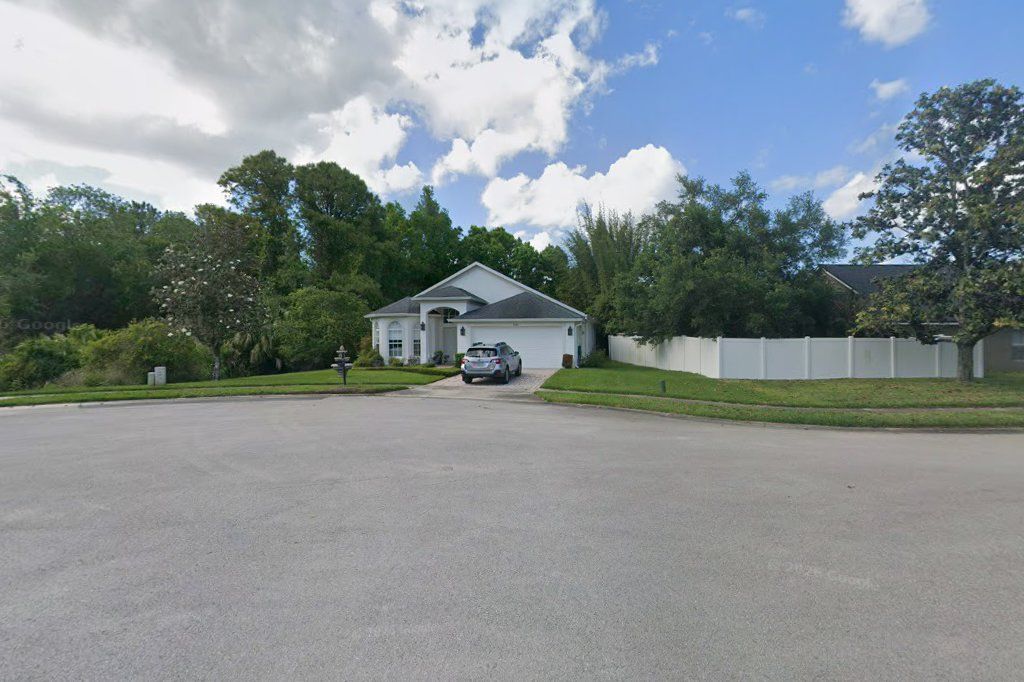 White one-story stucco home with a columned entry on Blue Springs Cove, Oviedo