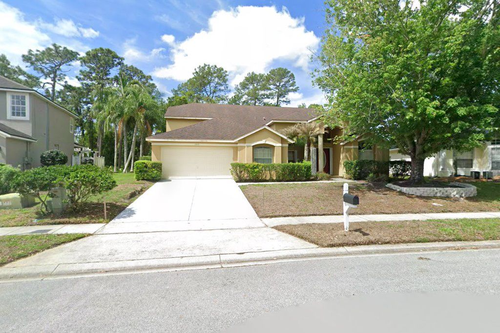 Two-story beige home with a three-car garage on Maidencane Loop, Oviedo